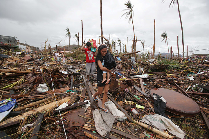 Typhoon Haiyan: A woman carries her baby across an area damaged by Typhoon Haiyan at Taclob