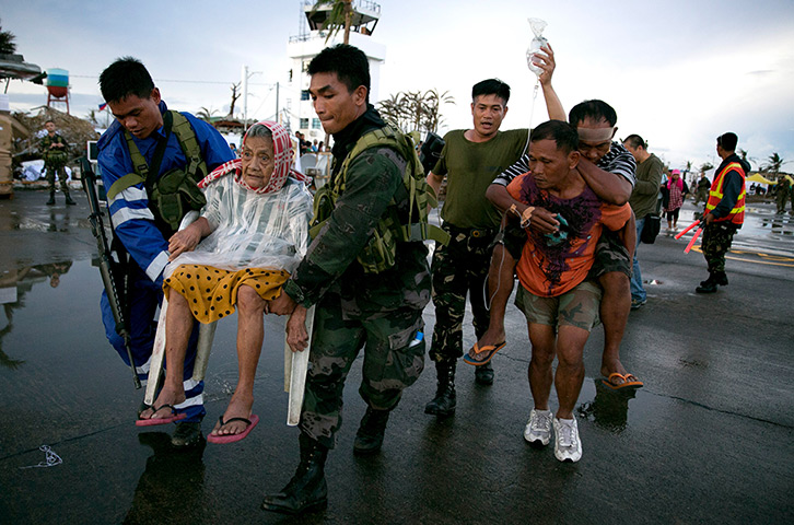 Typhoon Haiyan: An elderly lady and an injured man are carried to a waiting C130 aircraft d