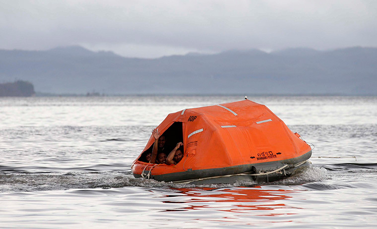 Typhoon Haiyan: Filipino rescuers from the Philippine Coast Guard ride on a life raft durin