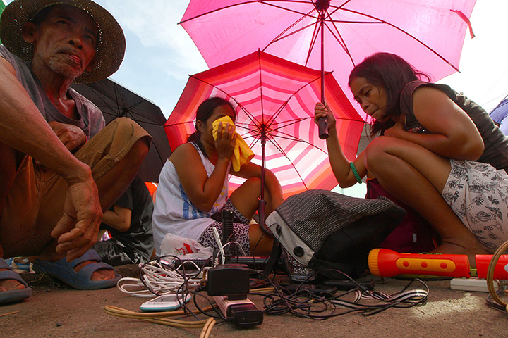 Haiyan aid: Typhoon survivors queue up to have their mobile phones charged using power 