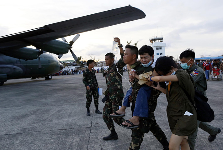 Haiyan aid: An injured typhoon survivor is carried by a military personnel,