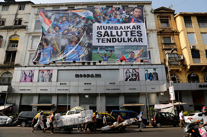 Tendulkar's last hurrah: Indian labourers move past a giant banner in Mumbai