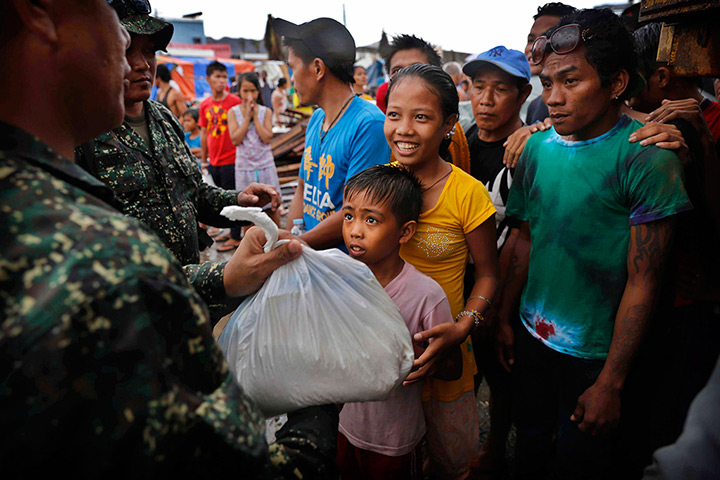 Philippines survivors: A young Filipino girl smiles as she and her brother receive their first bag