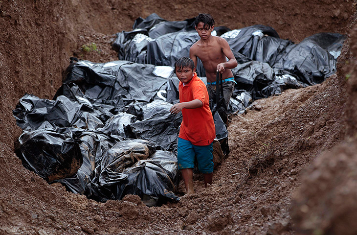 Philippines survivors: Filipino workers fill a large grave with body bags at the Basper public cem