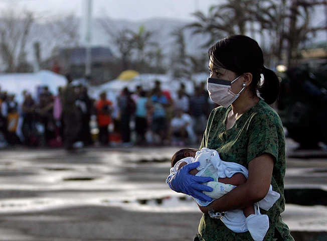 Philippines survivors: A Filipino Army nurse carries a seven day old infant for evacuation at the 