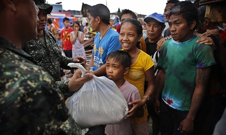 A young Filipino girl and her brother receive food aid at a centre in Tacloban