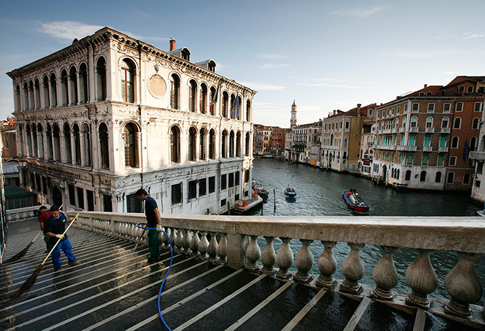 eyewitness: cities: Municipal workers clean the Rialto Bridge over the grand Canal in Venice