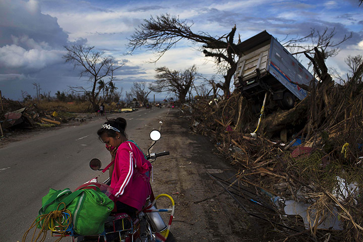 20 Photos: A woman rests on a roadside with her family's belongings near Tacloban