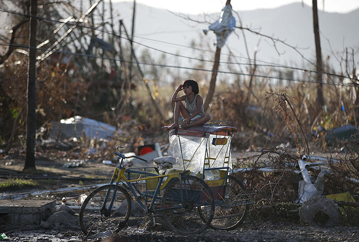 20 Photos: A girl on top of a pedicab in front of the damage caused by Typhoon Haiyan