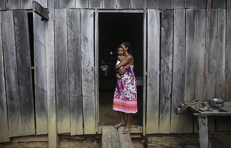 20 Photos: A woman holds her daughter outside their home in the Amazon rainforest