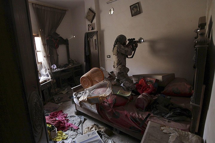 20 Photos: A Free Syrian Army fighter points his weapon through a hole in the wall
