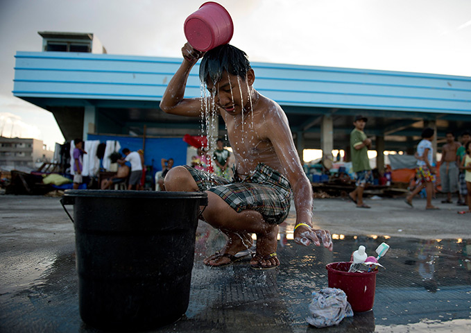 Weekend in pictures: Tacloban, Philippines: A boy washes himself outside a damaged warehouse used as accommodation for typhoon victims