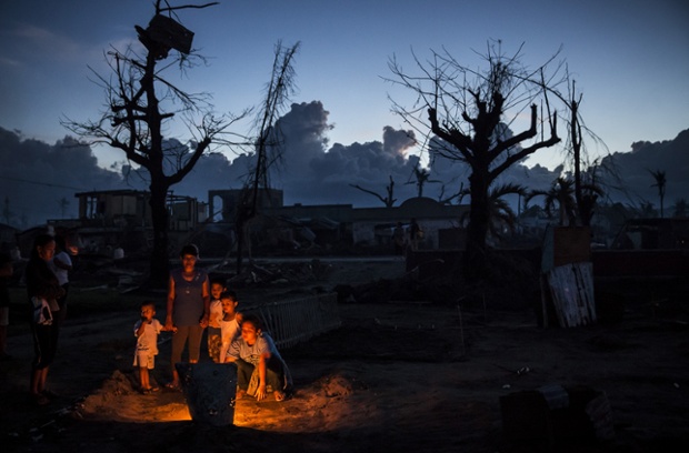 As night falls a family gather around the grave of a relative killed in the typhoon in Leyte. 