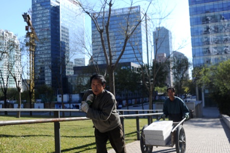 Two Chinese workers push and pull a trolley with building stones at a construction site in Beijing on November 18, 2013.