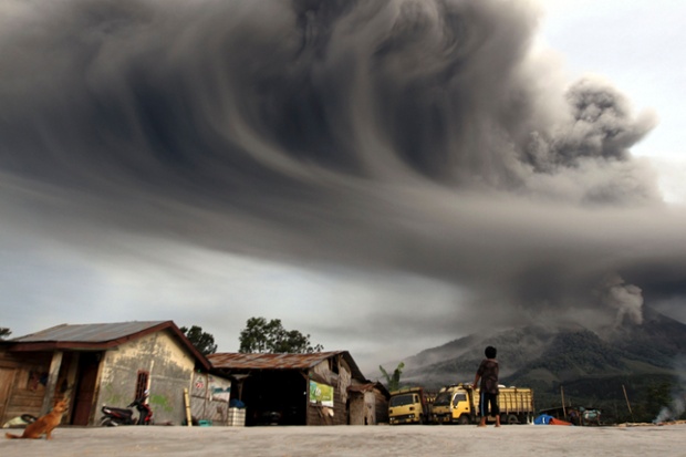 In an image that conveys the full force of nature, a woman watches the volcano Mount Sinabung erupting over the Karo district of Indonesia's north Sumatra.