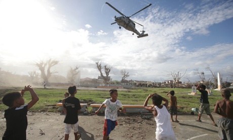 Help arrives. Typhoon survivors watch as a US helicopter lands to deliver relief goods in Tanauan, Leyte province, central Philippines today.