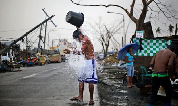 Um jovem filipino toma banho do lado de uma estrada em um bairro devastado pelo tufão Haiyan em Tacloban,.