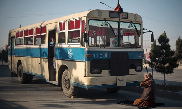 Um motorista de ônibus afegão oferece orações na frente de seu ônibus vazio.