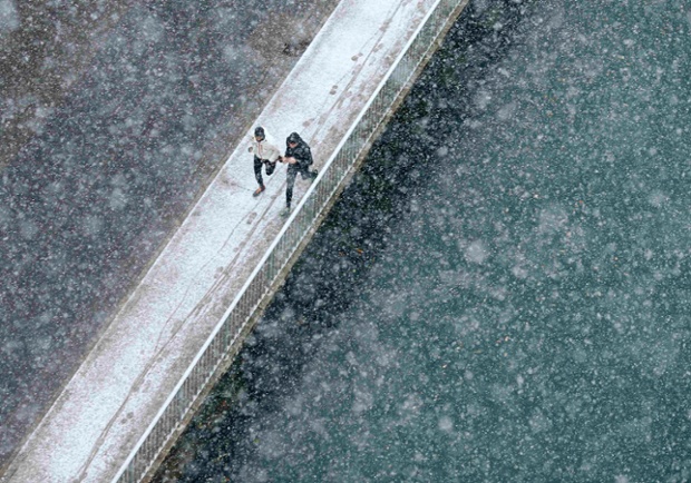 Dois corredores correr ao longo da margens do rio Aare, durante a primeira queda de neve em Berna, na Suíça, onde 5 a 15 cm de neve está prevista.