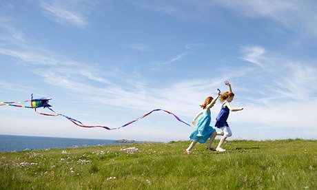 2 girls running with kites in field