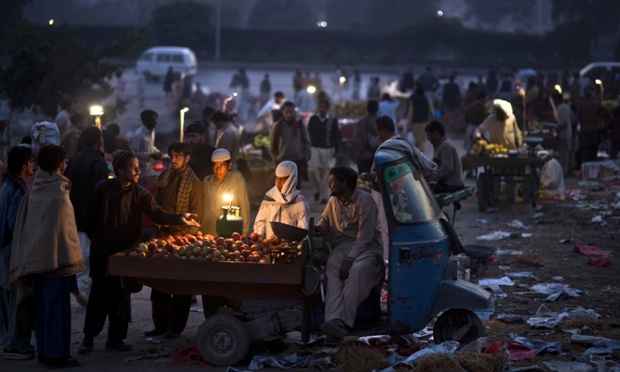 Um vendedor de frutas paquistanês usando seu riquixá para exibir maçãs à venda em Islamabad.