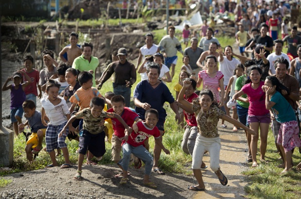 Residents scramble towards a Philippine Air Force helicopter delivering aid to a fishing village near Caragari.