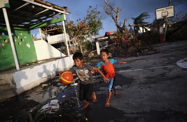 On a court wrecked by the typhoon, children play a game of basketball at sunset in Tacloban.