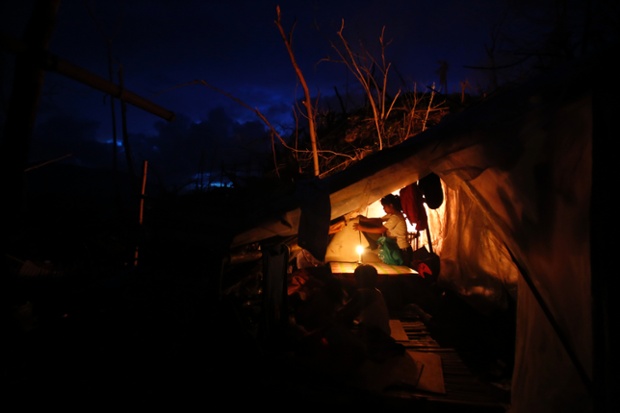 Homeless survivors are photographed in their makeshift shelter as night falls.