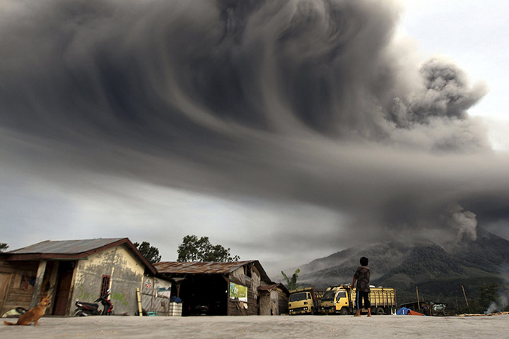 20 Photos: A woman looks on as Mount Sinabung spews ash