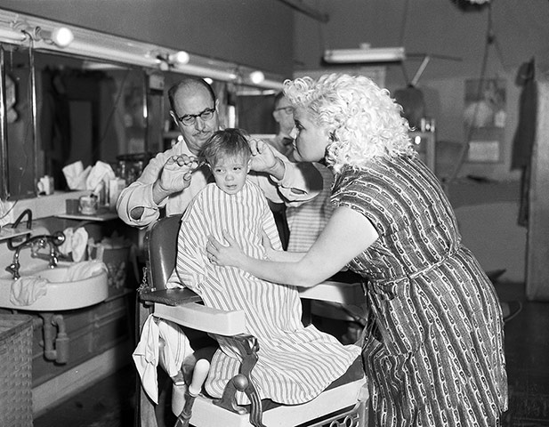 Big Picture - Revising : black and white photo of boy getting hair cut with man and woman