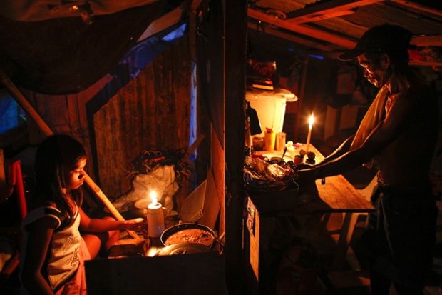Twelve year old Mary Joy Fabella cooks dinner for her family as her father opens canned fish in their makeshift shelter in the aftermath of Typhoon Haiyan in Palo in the Philippines. Survivors are still struggling with daily life after thousands had their homes and livelihoods destroyed by the typhoon.