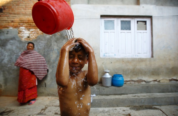 A little boy gets a shower in the street before leaving for school, in Lalitpur, Nepal.