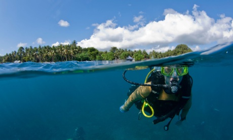 Female scuba diver surfacing with palm trees in the background