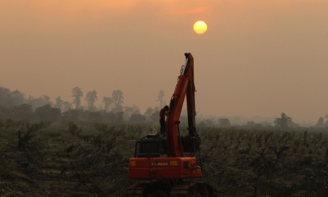 A worker washes himself on an excavator at a palm oil plantation near Dumai, as haze from clearance fires covers Indonesia's Riau province June 20, 2013. Demand for biofuel from palm oil and other crops has been blamed for creating secondary land clearance and increasing greenhouse gas emissions.