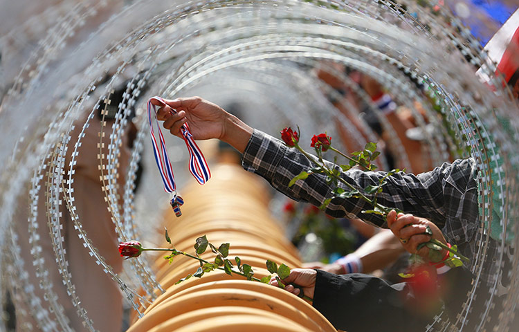 Thailand protests: A protester gives a rose and whistle to Thai soldiers