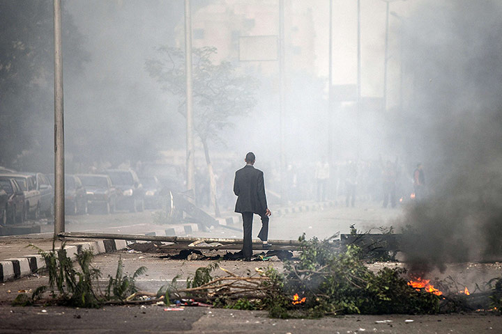 20 Photos: An Egyptian man walks amid teargas during clashes in Cairo