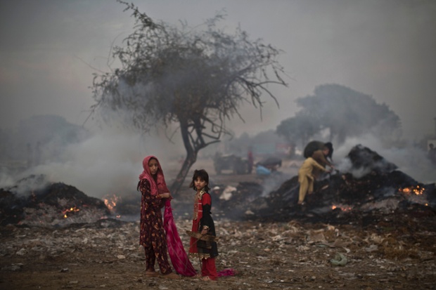 Children stand in a burning field which was used by fruit and vegetable sellers to store their wooden boxes on the outskirts of Islamabad, Pakistan. Local reports say the Capital Development Authority burned the field because it was used by the sellers for storage illegally.