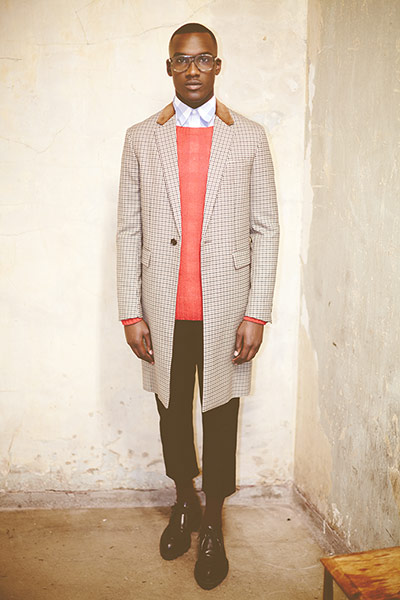 Fashion - boys and girls: man in checked coat and red jumper standing against stone wall