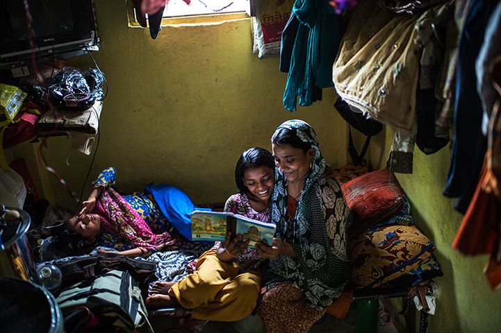 International Journalism: Mother reading to her daughter in their bedroom in Mumbai