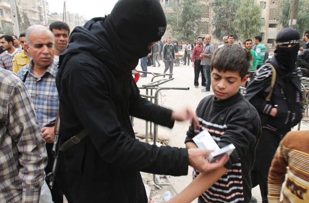 A boy is searched by a fighter in Aleppo