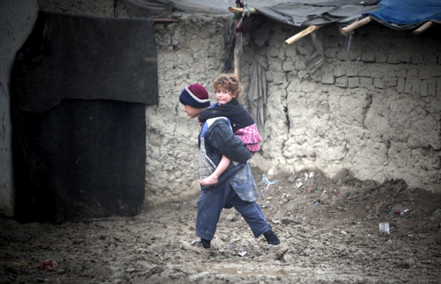 An Afghan boy carries his sister