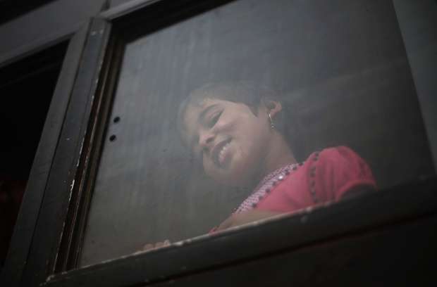 A girl looks out from a bus window on a street in New Delhi