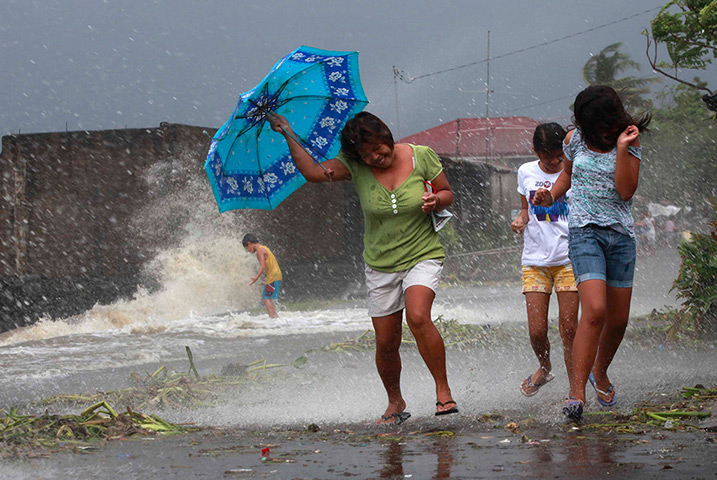 Typhoon updated: Residents walk along the coastal village while strong winds batter Bayog to