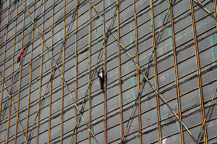 20 Photos: A woman with a portrait of her husband after climbing scaffolding in China