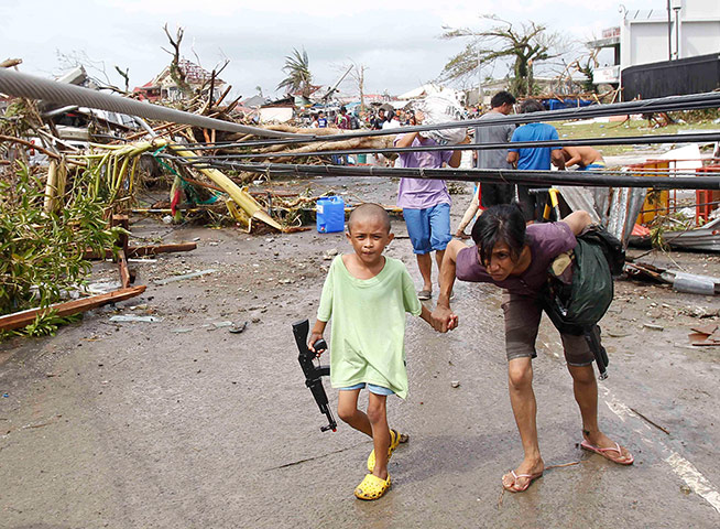 Typhoon Haiyan: A mother and her son walk under damaged electric cables 