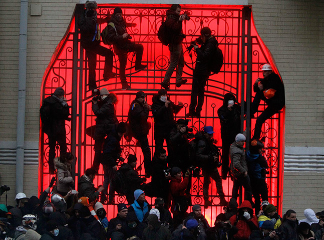 Ukraine protests: Protesters climb the gate of a building in Kiev