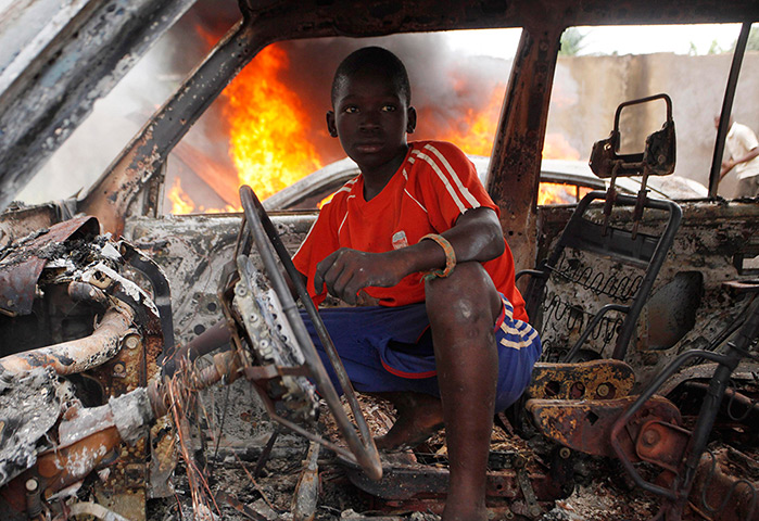 Central African Republic: A Christian youth squats inside a burnt out car in Bangui 