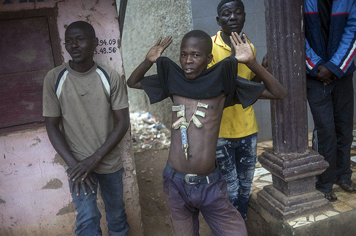 Central African Republic: A man holds up his top to show his charms against bullets during a disarmam