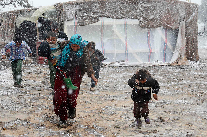 Winter in Syria: Syrian refugees run for cover from snow during a winter storm in the Bekaa 