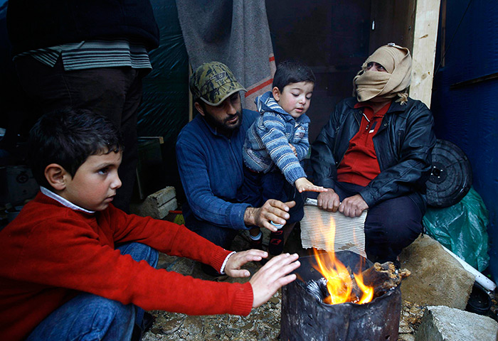 Winter in Syria: Syrian refugees warm themselves around a bonfire near their tent as a heavy